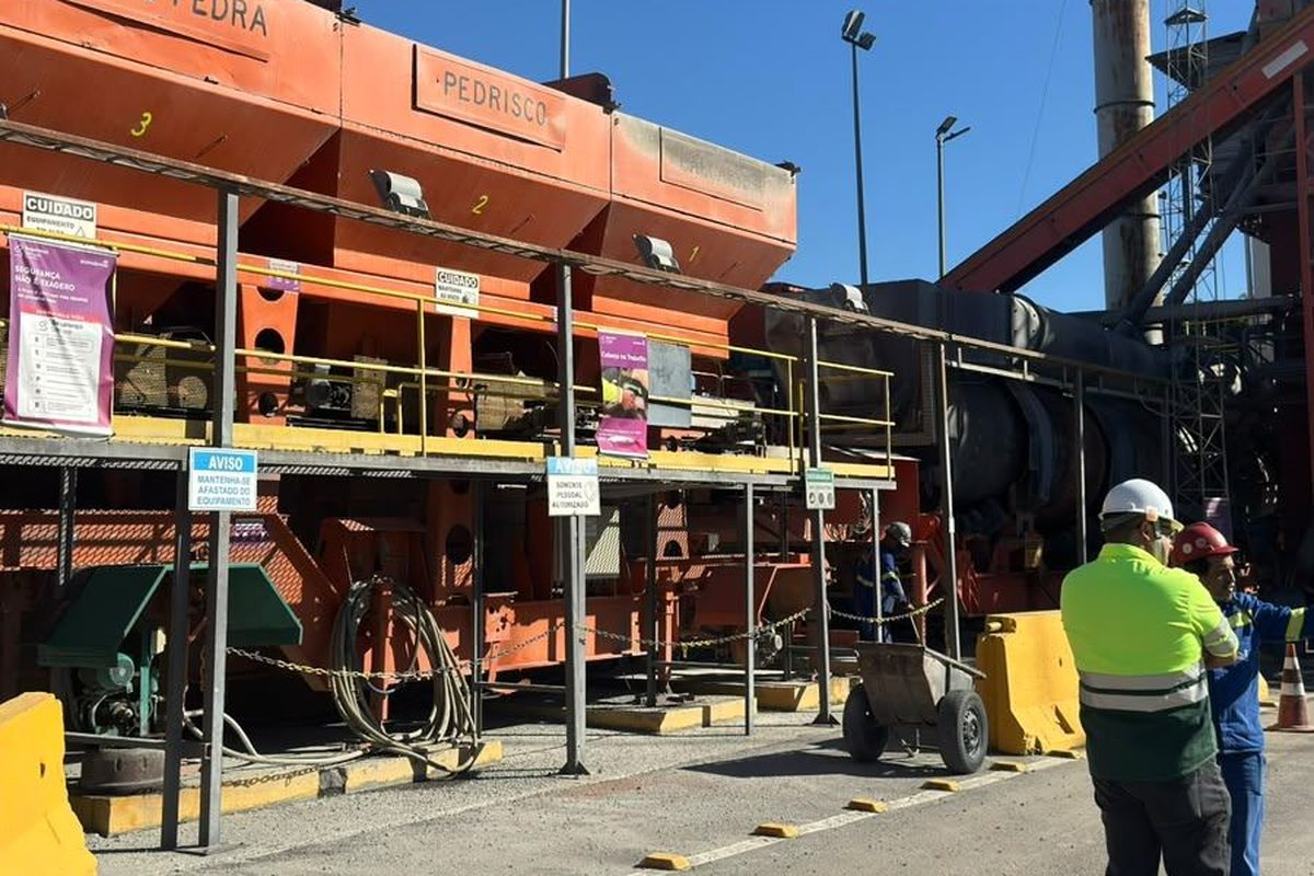 Trabalhadores com EPI em usina industrial a céu aberto