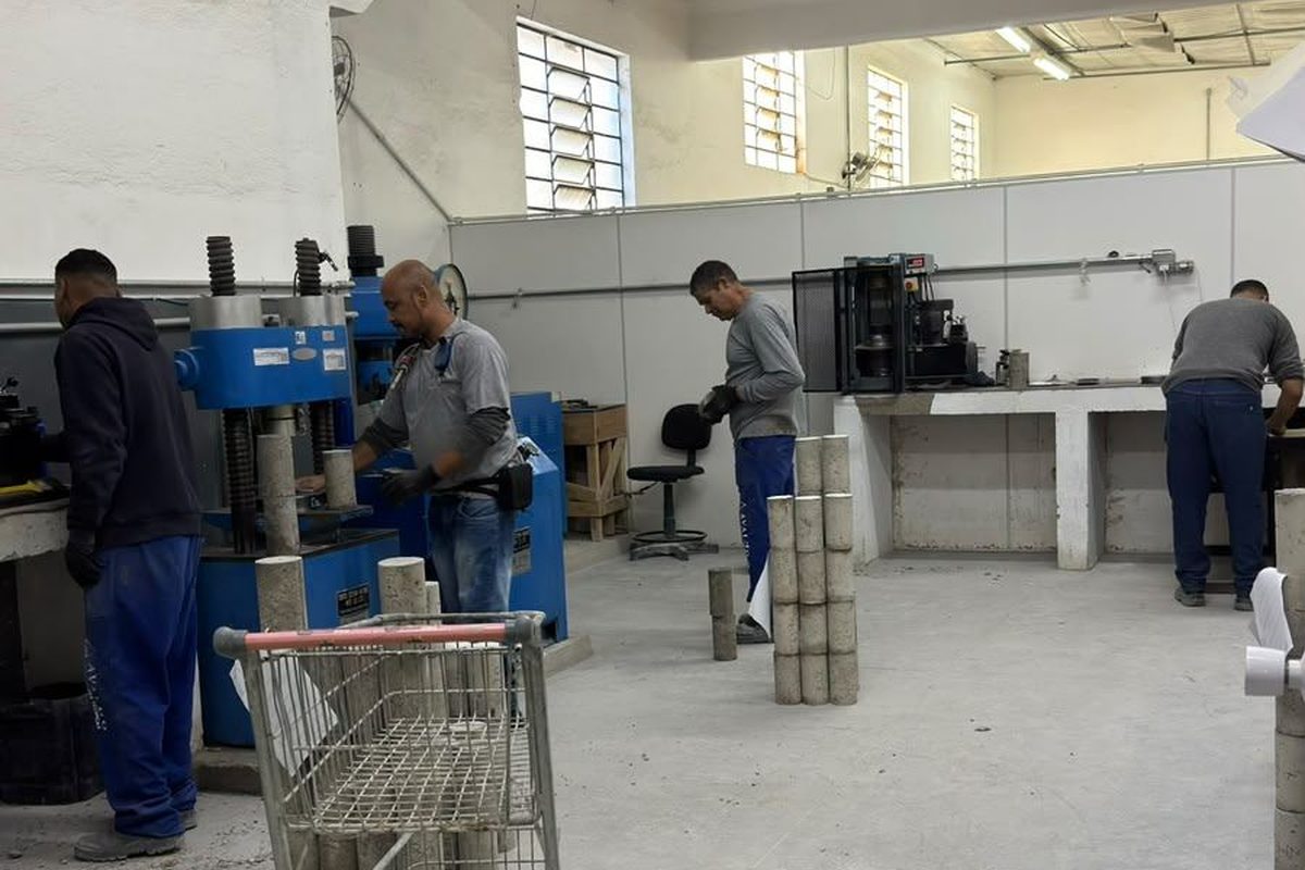 Laboratório rompendo corpos de prova de concreto em ensaio de resistência